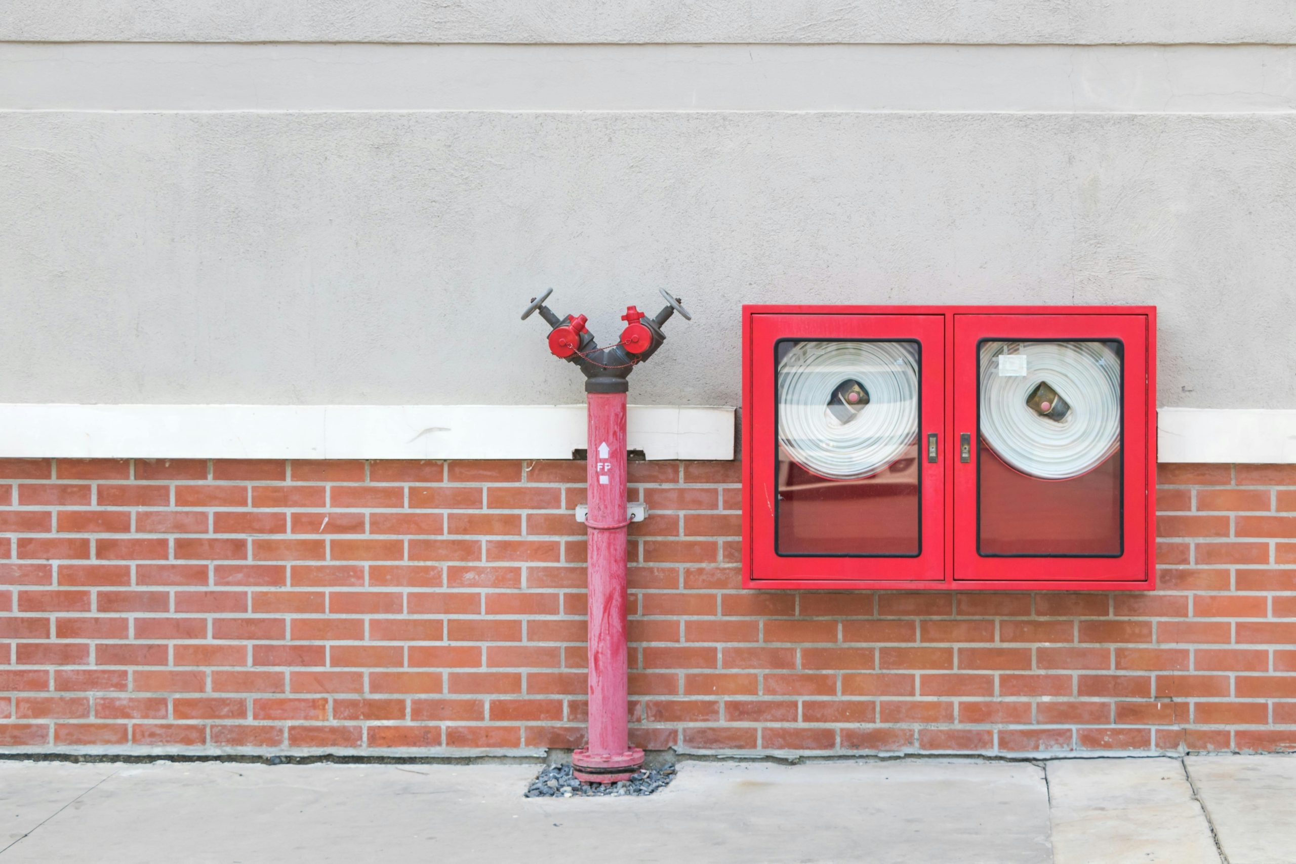 pexels photo 13060858 13060858 Outdoor fire hydrant and hoses against a brick wall, emphasizing fire safety.